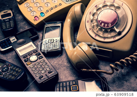 An old telephone with rotary dial, landline and obsoleted cellphone on a grunge background. An old telephone with rotary dial, landline and obsoleted cellphone on a grunge background. 63909518