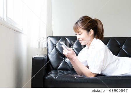 スマホでゆっくりゲームを楽しむ女性 スマホでゆっくりゲームを楽しむ女性 63909647