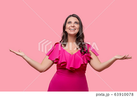 Woman in pink standing ecstatic with arms spread to the sides. 63910078
