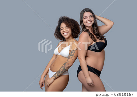 Two joyful girlfriends backs to each other in underwear. Two joyful girlfriends backs to each other in underwear. 63910167