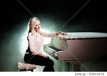 Pianist posing near white piano on the stage 63913019
