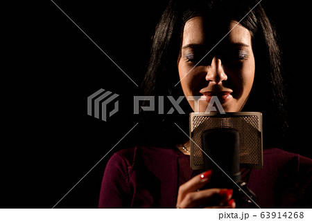 Portrait of woman recording a song in a professional studio 63914268
