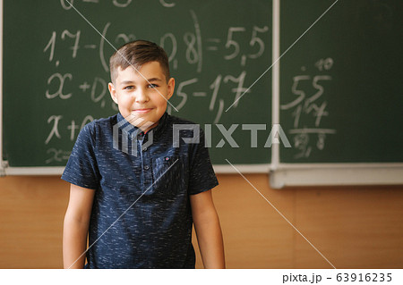 Cute boy stand in the classroom background of blackboard. Education. Elementary school Cute boy stand in the classroom background of blackboard. Education. Elementary school 63916235