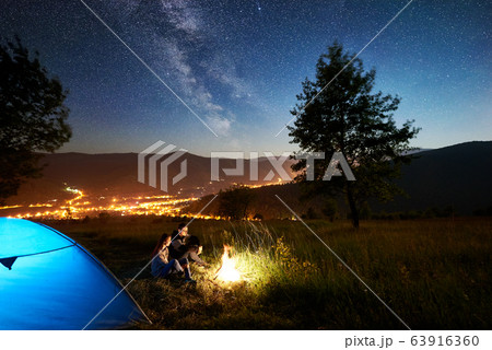 Couple tourists resting at night camping under stars Couple tourists resting at night camping under stars 63916360
