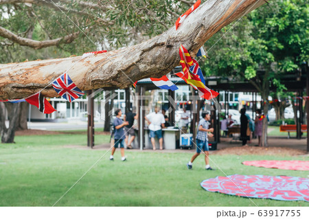 Flags of different countries in the tree branch with blured people in park doing barbecue together. Multicultural network, inclusivity concept 63917755