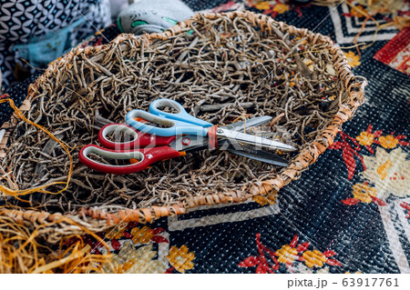 Handmade weave basket with scissors on table. Craft workshop. 63917761