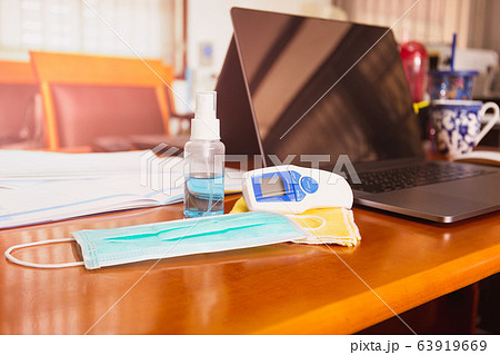Work from home concept alcohol spray bottle and thermometer on table with surgical mask virus protection. 63919669