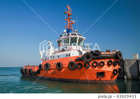 Tug boat with  bright orange hull 63920433