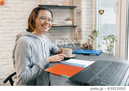 Portrait of young female student, high school student in coffee shop with laptop computer and cup of coffee, girl is studying, writing in notebook 63923092