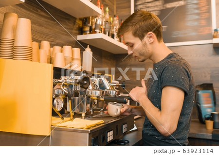 Young male coffee shop worker making coffee with machine Young male coffee shop worker making coffee with machine 63923114