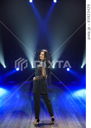 Female artist on the stage on dark background, smoke, blue spotlights Female artist on the stage on dark background, smoke, blue spotlights 63923429