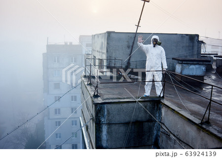 Worker scientist wearing protective coverall and gas mask doing ecological tests on the roof Worker scientist wearing protective coverall and gas mask doing ecological tests on the roof 63924139