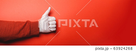 close-up female hand shows thumb up on red background 63924268