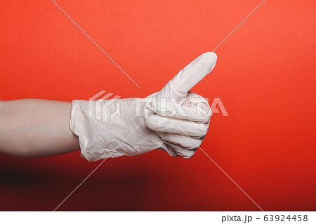 Child hand in big medical glove shows thumb up on red background 63924458