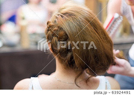 Hairdresser makes braid in beauty salon. No face. Hairdresser makes braid in beauty salon. No face. 63924491