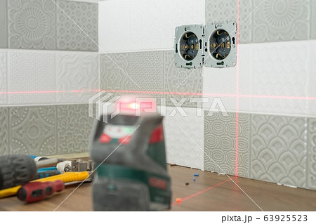 Electrician using infrared laser level to install electrical outlets. Renovation and construction in kitchen 63925523