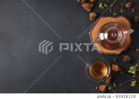Chaga beverage in glass cup and teapot on black. Chaga beverage in glass cup and teapot on black. 63926119