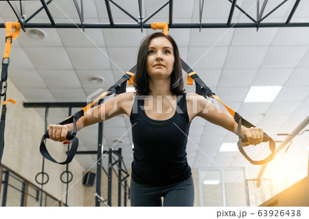 Young beautiful sporty woman exercising on fitness straps system in gym. Fitness, sport, training, and healthy lifestyle concept. Young beautiful sporty woman exercising on fitness straps system in gym. Fitness, sport, training, and healthy lifestyle concept. 63926438