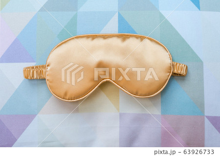 Golden sleeping eye mask on the bed, top view. Golden sleeping eye mask on the bed, top view. 63926733