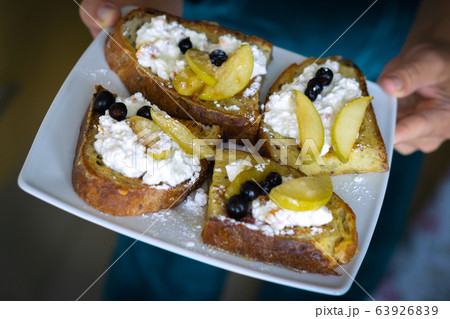 Woman holds white plate with Homemade rispbread toast with Cottage Cheese, sliced apples and black curant Woman holds white plate with Homemade rispbread toast with Cottage Cheese, sliced apples and black curant 63926839