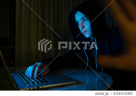 Hacker with a laptop hiding his face by hand. 63932080