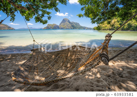 El Nido, Palawan, Philippines. A bamboo hammock in the shade with beautiful tropical cadlao island in morning light the background 63933581