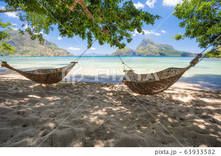 El Nido, Palawan, Philippines. Bamboo hammocks on shore in the shade. Beautiful tropical lagoon with epic Cadlao island in background 63933582