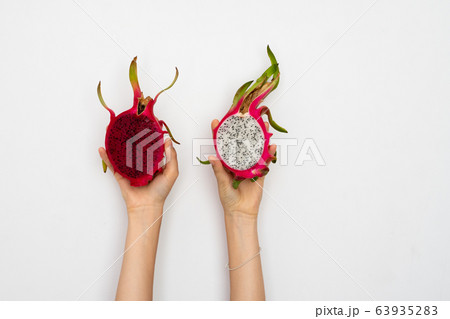 Female hands holding a two half of the ripe dragon fruit on white background. Female hands holding a two half of the ripe dragon fruit on white background. 63935283