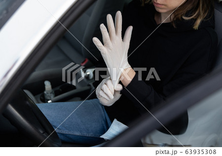 Woman in protective medical mask is wearing rubber gloves for protect himself from bacteria virus while planning to drive. Protective mask while quarantine, pandemic, covid 19, coronavirus, infection. 63935308
