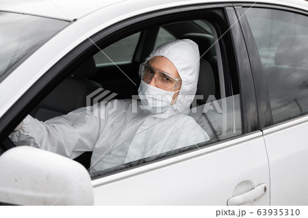 Man in protective suit, medical mask and rubber gloves for protect from bacteria and virus is planning to drive. Protective mask while quarantine, world pandemic, covid 19, coronavirus, infection. Man in protective suit, medical mask and rubber gloves for protect from bacteria and virus is planning to drive. Protective mask while quarantine, world pandemic, covid 19, coronavirus, infection. 63935310