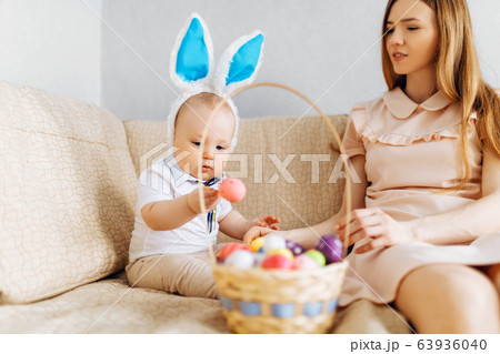 Mother and baby with rabbit ears, with Easter eggs 63936040