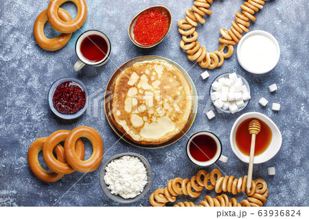 Shrovetide Maslenitsa festival meal. Russian pancake blini with raspberry jam, honey, fresh cream and red caviar,sugar cubes,cottage cheese,bubliks on dark background 63936824