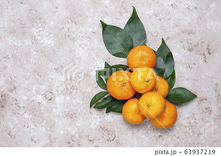 Tangerines (oranges, clementines, citrus fruits) with green leaves on concrete background with copy space 63937219