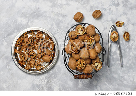 Whole walnuts in shell in food metal basket, walnut kernels. Top view on concrete background 63937253