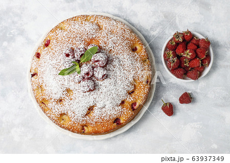 Simple cake with powdered sugar and fresh raspberries on a light background. Summer berry dessert. 63937349