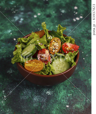 Fresh lettuce salad with yellow tomatoes,ccumber slices,cherry tomatoes,seeds onceramic bowl on dark background,diet food,vegetarian salad,healthy eating concept Fresh lettuce salad with yellow tomatoes,ccumber slices,cherry tomatoes,seeds onceramic bowl on dark background,diet food,vegetarian salad,healthy eating concept 63937823