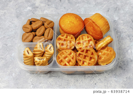Unhealthy lunch box with cookies,waffles.muffins on concrete background 63938714