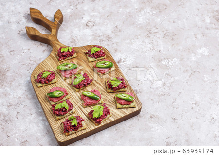Beetroot hummus canapes withgreen pepper slices and parsley on cutting board on light background 63939174