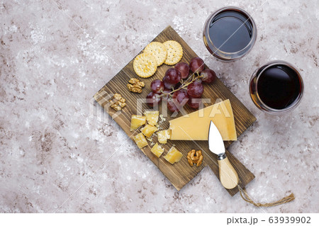 cheese board with hard cheese ,cheese knife,red wine glass,grape on brown concrete background 63939902