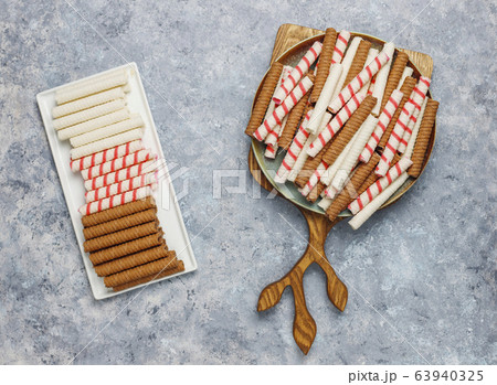 Plate with tasty wafer roll sticks on concrete background, top view. Crispy food Plate with tasty wafer roll sticks on concrete background, top view. Crispy food 63940325