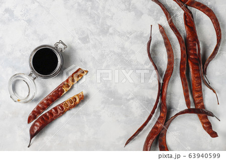 Carob syrup in glass jar with carob pods and seeds on light background Carob syrup in glass jar with carob pods and seeds on light background 63940599