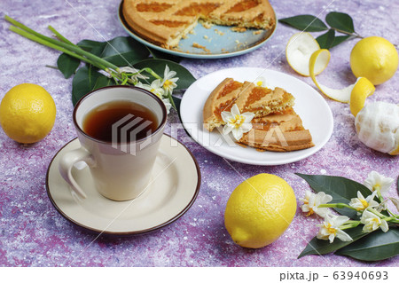 Delicious lemon pie slices with fresh lemons and a cup of tea on light background,top view 63940693