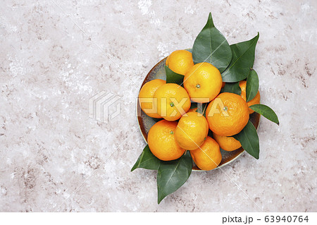 Tangerines (oranges, clementines, citrus fruits) with green leaves on concrete background with copy space 63940764