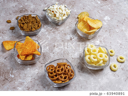 Salty snacks. Pretzels, chips, crackers,popcorn in bowls. Unhealthy products. food bad for figure, skin, heart and teeth. Assortment of fast carbohydrates food 63940891