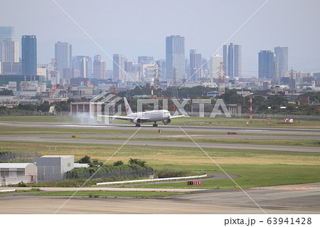 大阪のビル群を背景に着陸する日本航空機 63941428