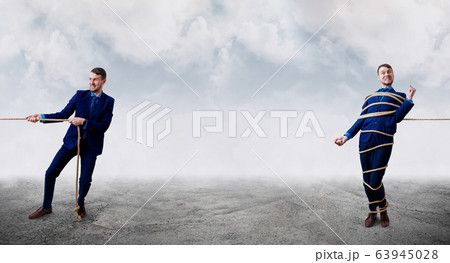 Angry businessman pulls tied himself with a rope. 63945028