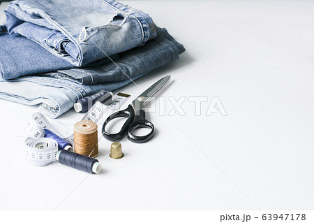Handicraft, clothing repair. Ripped blue jeans sewing accessories white background. The concept of economical things. Handicraft, clothing repair. Ripped blue jeans sewing accessories white background. The concept of economical things. 63947178