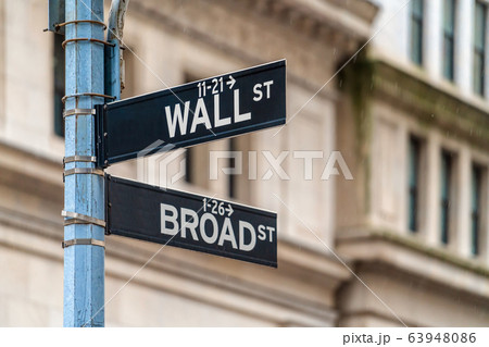 Wall Street "WALL ST" sign and broadway street over NYSE stock market exchange building background. The New York Stock Exchange locate in economy district, Business and sing of landmark concept 63948086