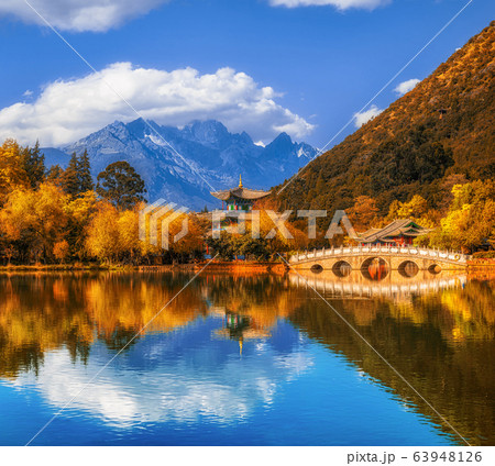 Landscape view of the Black Dragon Pool at Jade Spring Park with marble bridge over the Jade dragon mountain under blue sky, Lijiang, Yunnan province, China. China culture and travel concept 63948126
