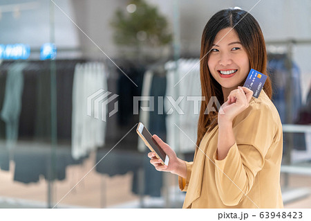 Portrait Asian woman using credit card with smart mobile phone for online shopping in department store over the clothes shop store background, technology money wallet and online payment concept Portrait Asian woman using credit card with smart mobile phone for online shopping in department store over the clothes shop store background, technology money wallet and online payment concept 63948423